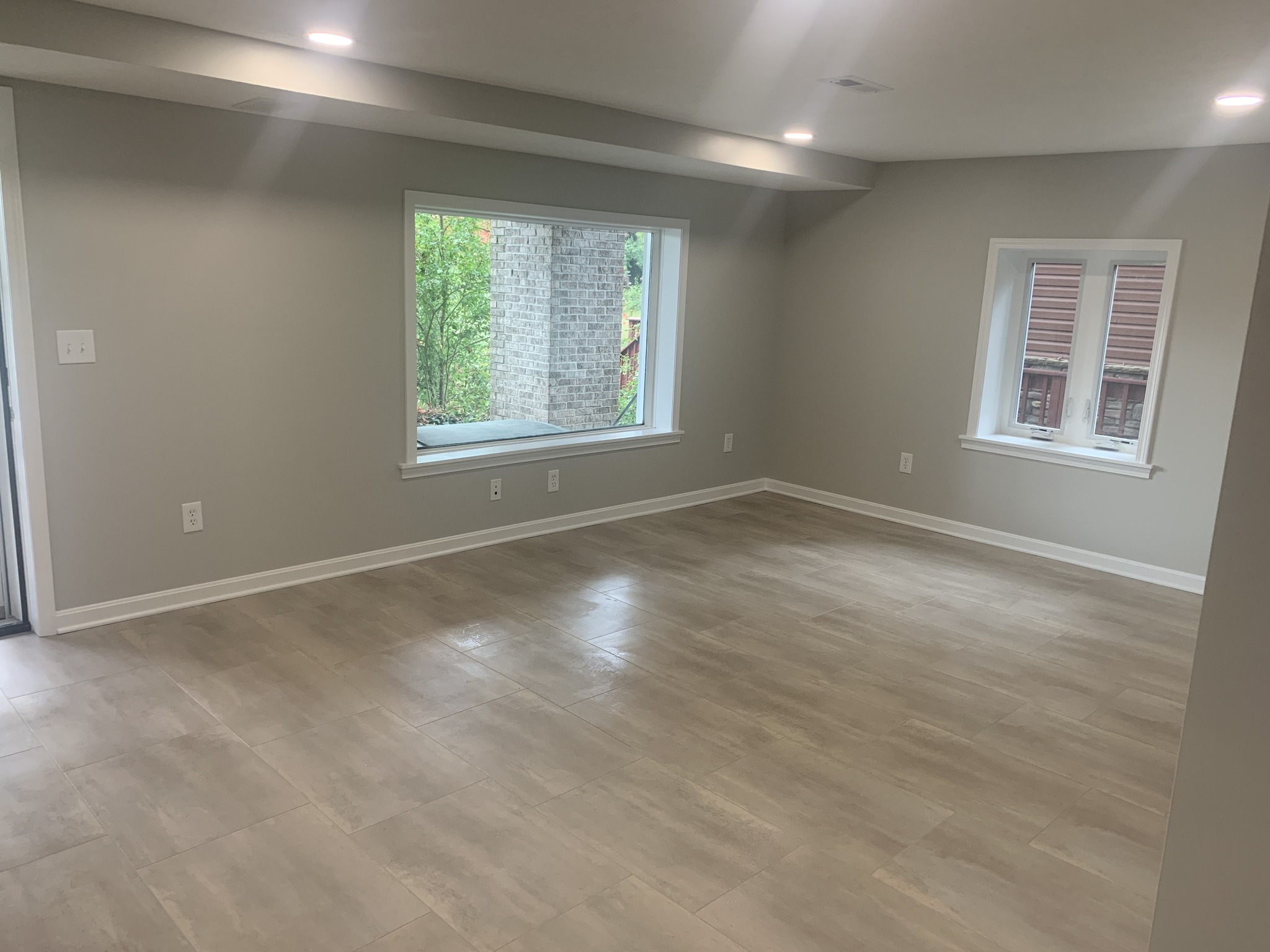 Remodeled basement with recessed lighting and tile flooring